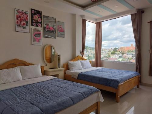 a bedroom with two beds and a large window at Cam Ly Homestay in Da Lat
