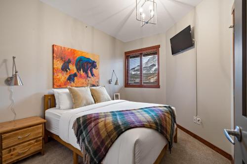 a bedroom with a bed and a painting on the wall at RidgeView Loft - Top Floor 2 Bed 2 Bath, Amazing Views in Canmore