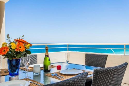 un tavolo con una bottiglia di vino e un vaso di fiori di Beach View Apartment in Cottesloe a Perth
