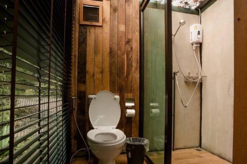 a bathroom with a toilet in a wooden wall at Wilderness Treehouse in Doi Saket