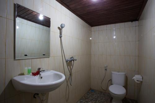 a bathroom with a sink and a toilet and a mirror at Klumpu Hill Villas Nusa Penida in Nusa Penida