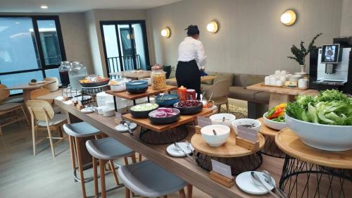 una mujer parada en una habitación con una mesa de comida en Wellness Stay & Hotel Sukhumvit 107 en Bangna