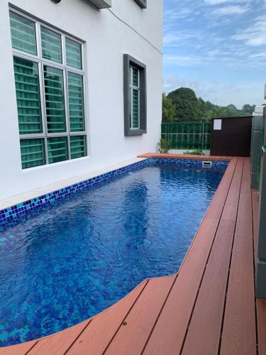 einen Pool mit einer Holzterrasse neben einem Haus in der Unterkunft A home with private pool, Kebun Kecil in Tangga Batu