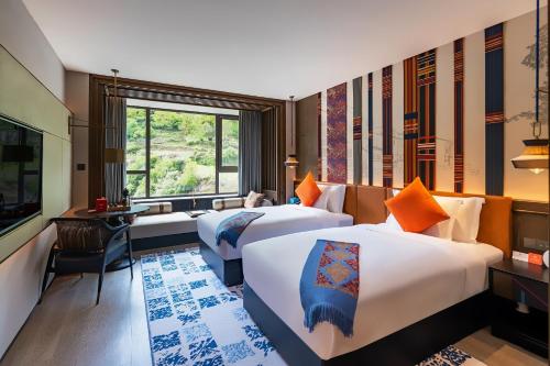 九寨溝にあるHotel Indigo Jiuzhai, an IHG Hotelのベッド2台と窓が備わるホテルルームです。