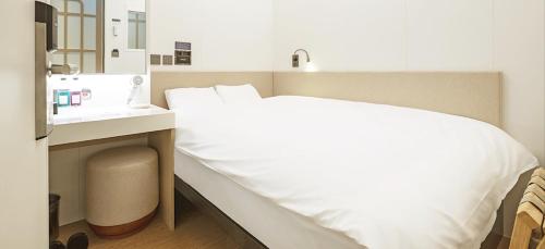 een slaapkamer met een wit bed en een wastafel bij DarakHyu Yeosu Capsule Hotel by WALKERHILL in Yeosu