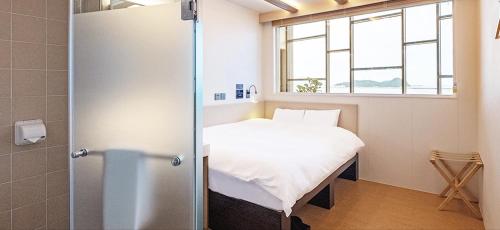 een kleine kamer met een bed en een raam bij DarakHyu Yeosu Capsule Hotel by WALKERHILL in Yeosu