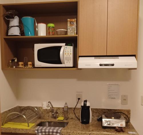 a kitchen counter with a microwave and a sink at Lindo Flat em resort silencioso e aconchegante in Brasília