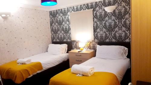 Penzance Cottage في بينزانس: سريرين في غرفة ذات أغطية صفراء وبيضاء