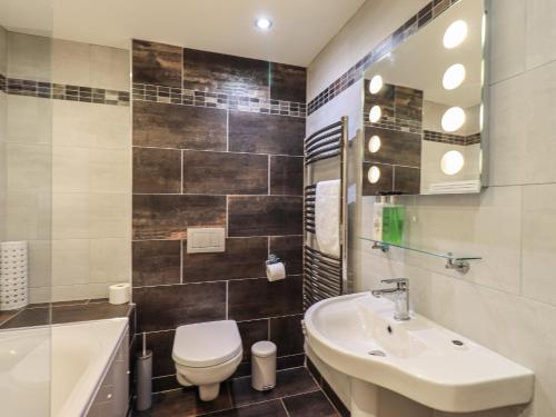 ein Badezimmer mit einem Waschbecken, einem WC und einer Badewanne in der Unterkunft Riverside Park 1 in Keswick
