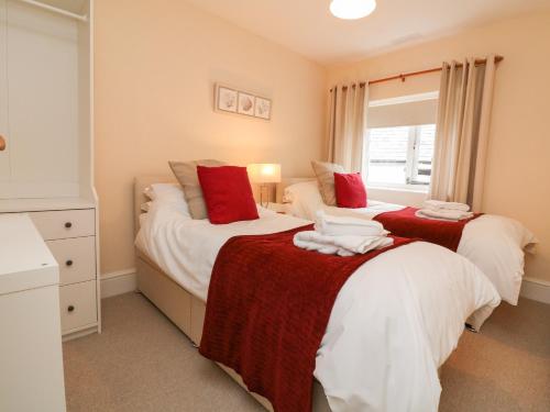 a bedroom with two beds with red and white blankets at Courtyard Cottage in Chittlehampton