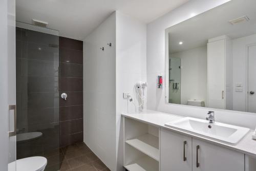 a white bathroom with a sink and a shower at Lantern 3 Bedroom Terrace with majestic mountain view in Thredbo
