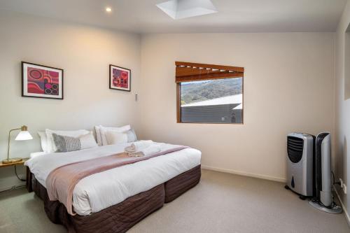 um quarto com uma cama grande e uma janela em Snow Stream 2 Bedroom and loft with gas fire balcony and garage parking em Thredbo