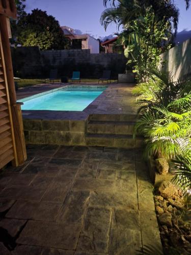 a swimming pool with a stone walkway next to a house at LODGE INDIGO - Bungalow & RDC indépendant proche aéroport in Sainte-Marie
