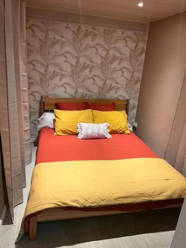 uma cama grande com um cobertor amarelo e vermelho em Rez-de-chaussée indépendant avec piscine em Sainte-Marie