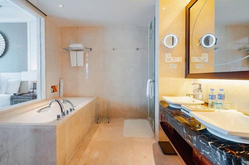 a bathroom with two sinks and a tub and a shower at Pullman Haikou in Haikou