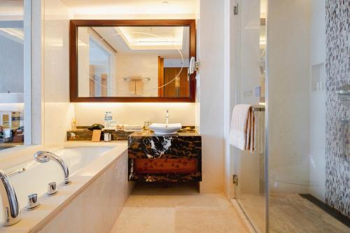 a bathroom with a tub and a sink and a mirror at Pullman Haikou in Haikou