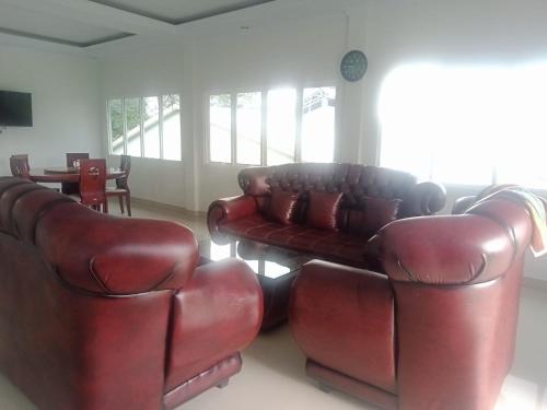 a living room with two leather couches and a table at Homestay Almanda Syariah Malino in Sungguminasa