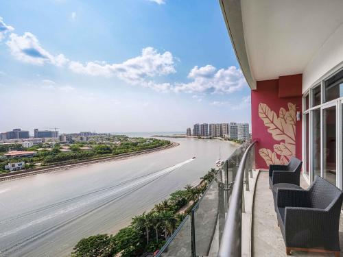 a balcony with chairs and a view of the ocean at Pullman Haikou in Haikou