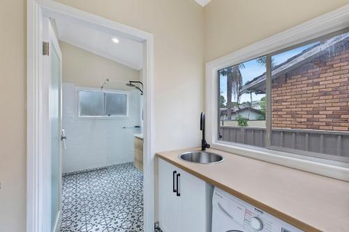La salle de bains est pourvue d'un lavabo et d'une fenêtre. dans l'établissement Cottage Hideaway - Pet Friendly, à Budgewoi