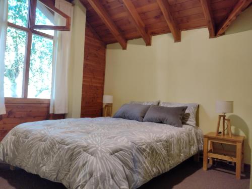 1 dormitorio con cama y ventana grande en Cabañas El Estribo Sur Bariloche en San Carlos de Bariloche