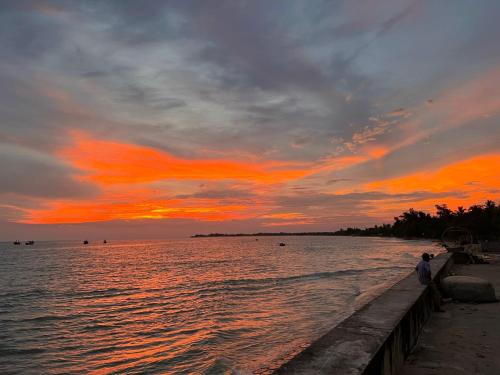 a person standing on a pier near the water at sunset at Lê Huỳnh Guest House Family in Ke Ga
