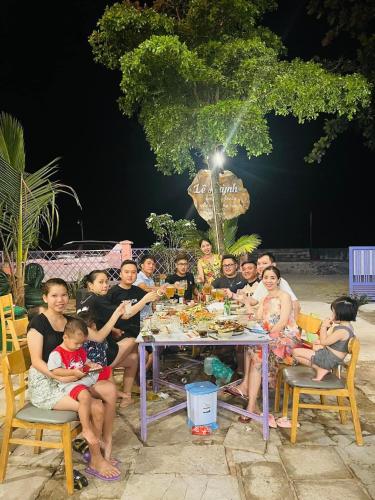 a group of people sitting around a table at Lê Huỳnh Guest House Family in Ke Ga