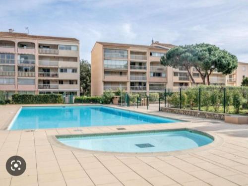 une piscine vide en face d'un bâtiment dans l'établissement Studio cabine avec balcon, piscine et parking - Sainte Maxime - FR-1-226-509, à Sainte-Maxime