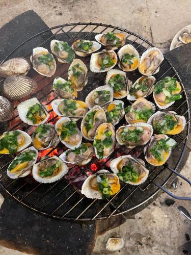 a bunch of oysters are cooking on a grill at Lê Huỳnh Guest House Family in Ke Ga