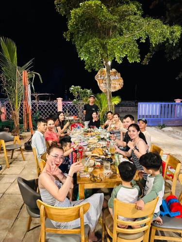 a group of people sitting around a long table at Lê Huỳnh Guest House Family in Ke Ga