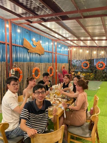a group of people sitting at a table in a restaurant at Lê Huỳnh Guest House Family in Ke Ga