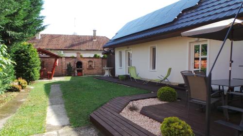 un patio trasero con una terraza de madera y una casa en Rozalia Apartman, en Gyula