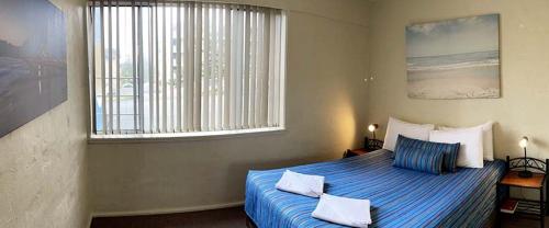 a bedroom with a bed with blue sheets and a window at Waterview Apartments in Port Macquarie