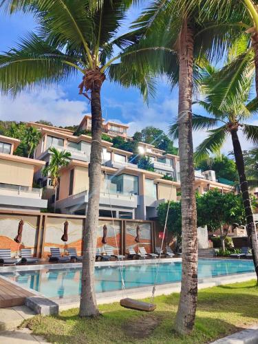a hotel with palm trees in front of a swimming pool at Bandara Pool Villas, Phuket in Panwa Beach