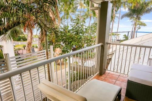 a balcony with a chair and palm trees at Paradise On The Beach Resort in Palm Cove