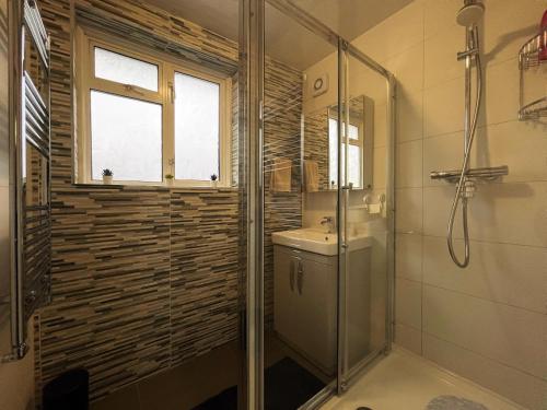 a bathroom with a glass shower and a sink at Nelly's Place hosted by AirOperate in Wealdstone