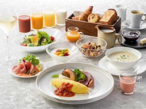 a table with plates of breakfast foods and drinks at Portom International Hokkaido in Chitose