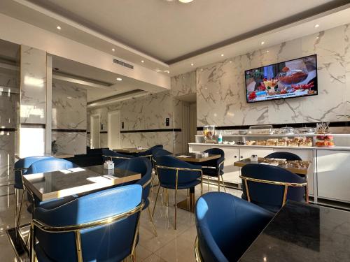 a restaurant with blue chairs and a tv on the wall at Hotel Midway in Milan
