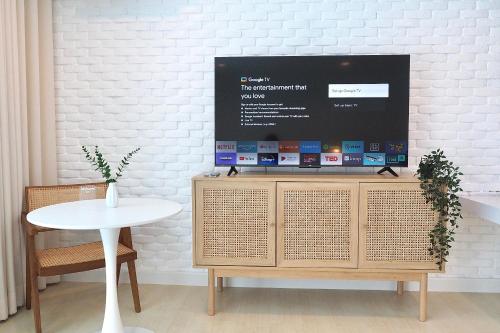 a tv on top of a wooden cabinet with a table at Beachfront Deluxe pool access room one-minute walk to Wonnapha beach FREE DISNEY PLUS in Bangsaen