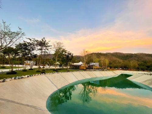 a pool of water with a sunset in the background at The Wild Khao Yai in Klang Dong