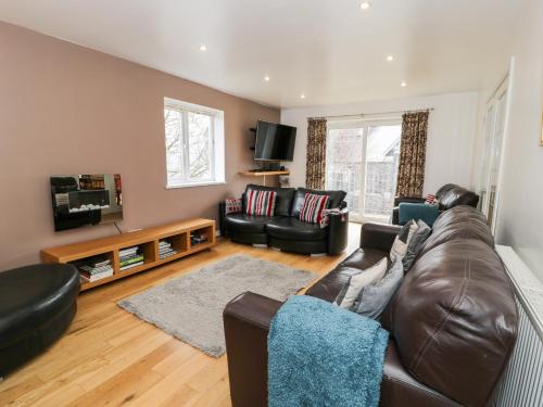 a living room with a leather couch and a tv at Ty Coch in Llanberis