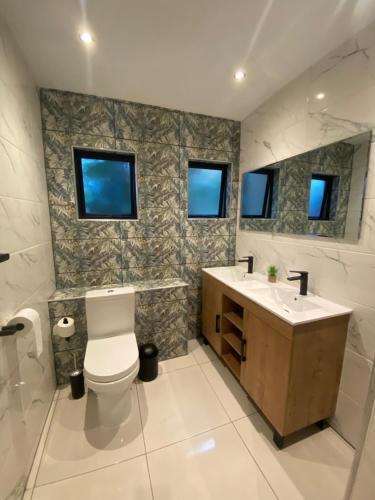 a bathroom with a toilet and a sink and two windows at The Bridge UNIT 23 St Lucia in St Lucia