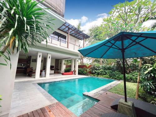 a pool with an umbrella next to a house at Villa Sally in Canggu