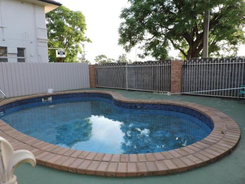 a small swimming pool with a wooden deck around it at Red Cliffs Colonial Motor Lodge, Mildura Region in Red Cliffs