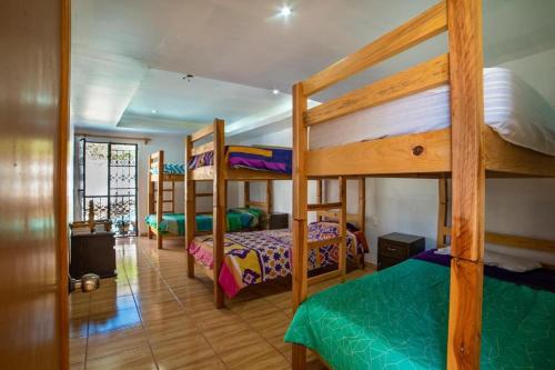 a room with three bunk beds in a house at Hostal Casa Pajaritos in Taxco de Alarcón