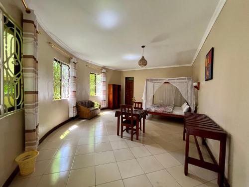 - un salon avec une table, des chaises et un lit dans l'établissement Charming Bungalows, à Mwanza