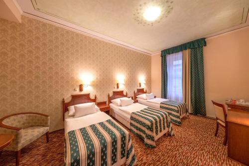 a hotel room with two beds and a desk at Hotel Meteor Plaza Prague in Prague