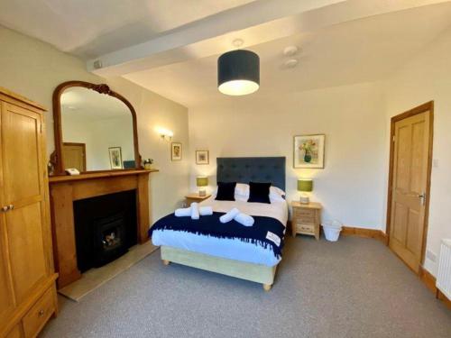 1 dormitorio con cama, chimenea y espejo en Elegant & spacious farmhouse with wonderful views, en Penrith