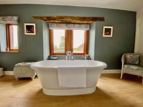 a large bath tub in a room with a window at Elegant & spacious farmhouse with wonderful views in Penrith