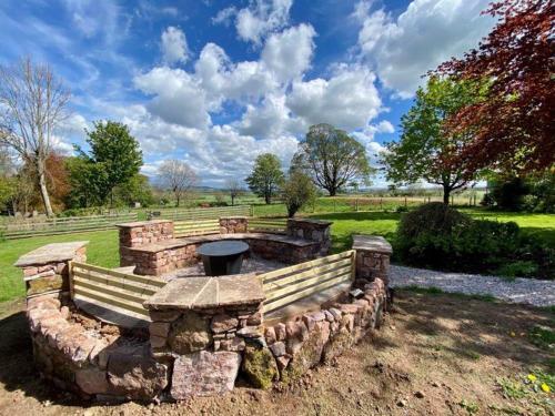 a stone bench with a grill in a park at Elegant & spacious farmhouse with wonderful views in Penrith