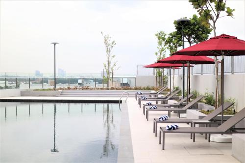 une piscine avec bancs et parasols à côté d'un bâtiment dans l'établissement KSL ESPLANADE HOTEL with HOT SPRING, à Klang